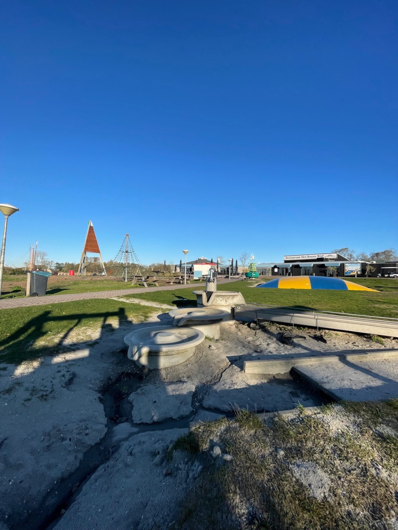 Spielplätze Spielplatz mit bunten Flächen, einem Turm im Hintergrund und klarem, blauem Himmel.