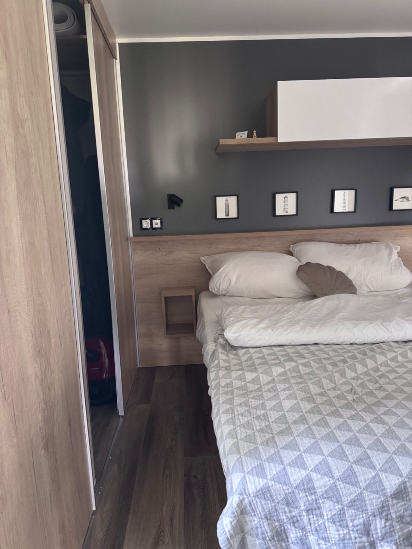 Hauptschlafzimmer Helles Schlafzimmer mit einem Bett, Holzregalen und grauen Wänden.