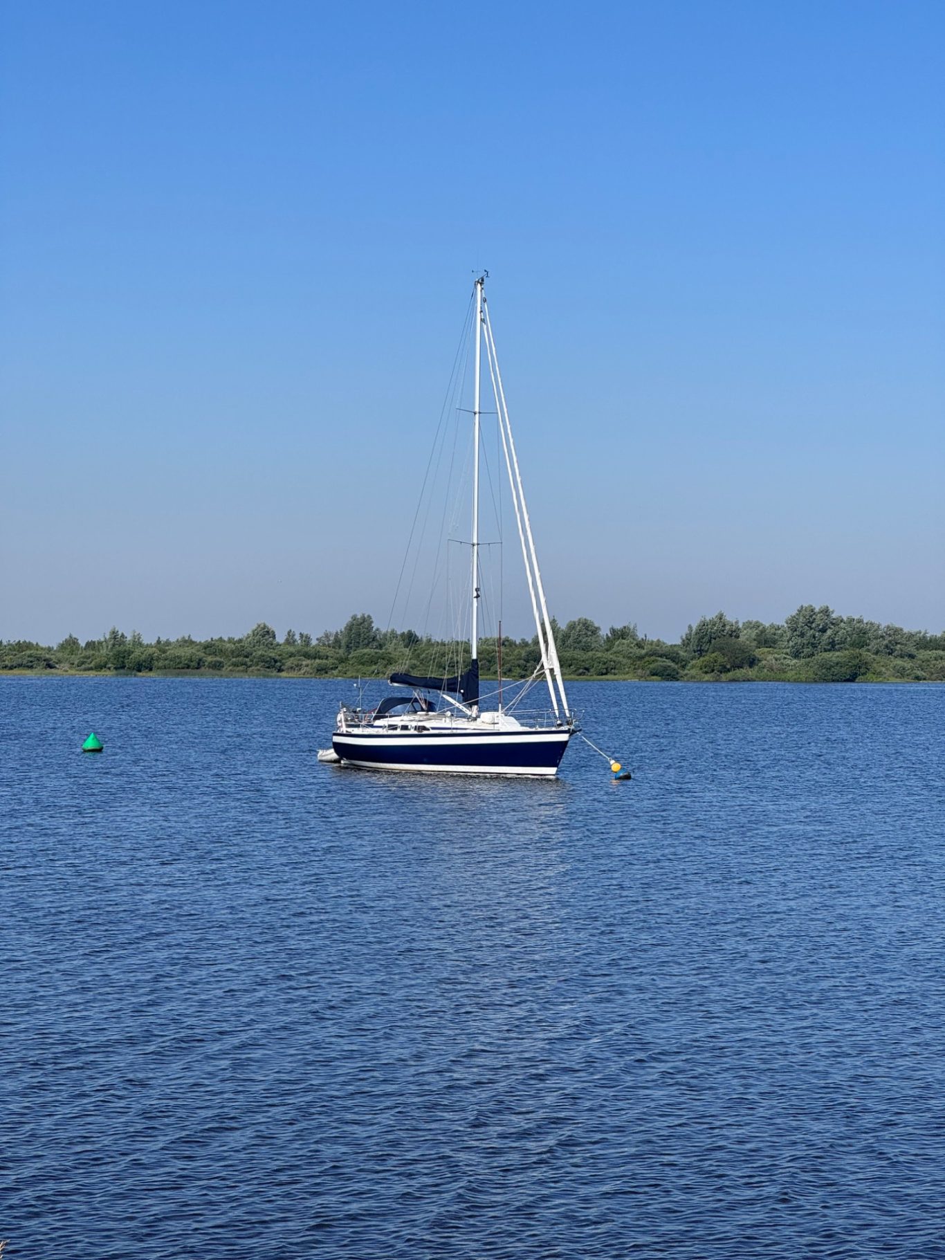 Segeln Ein Segelboot schaukelt ruhig auf einem blauen Gewässer unter klarem Himmel.