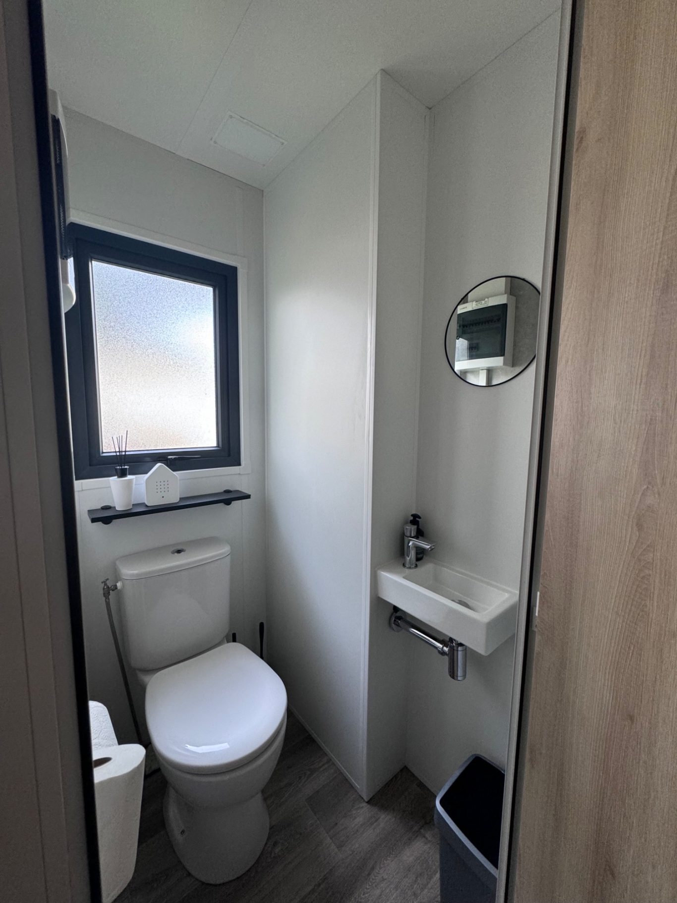 Toilette Kleines Badezimmer mit Toilette, Waschbecken und rundem Spiegel.
