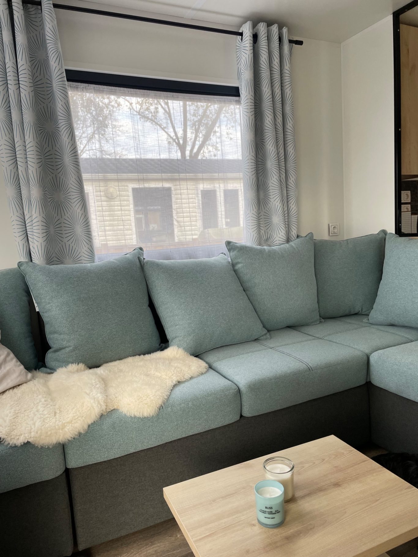 Couch Gemütliche Wohnzimmerecke mit hellblauem Sofa und einem Tisch. Vorhänge und Fenster leicht beschlagen.