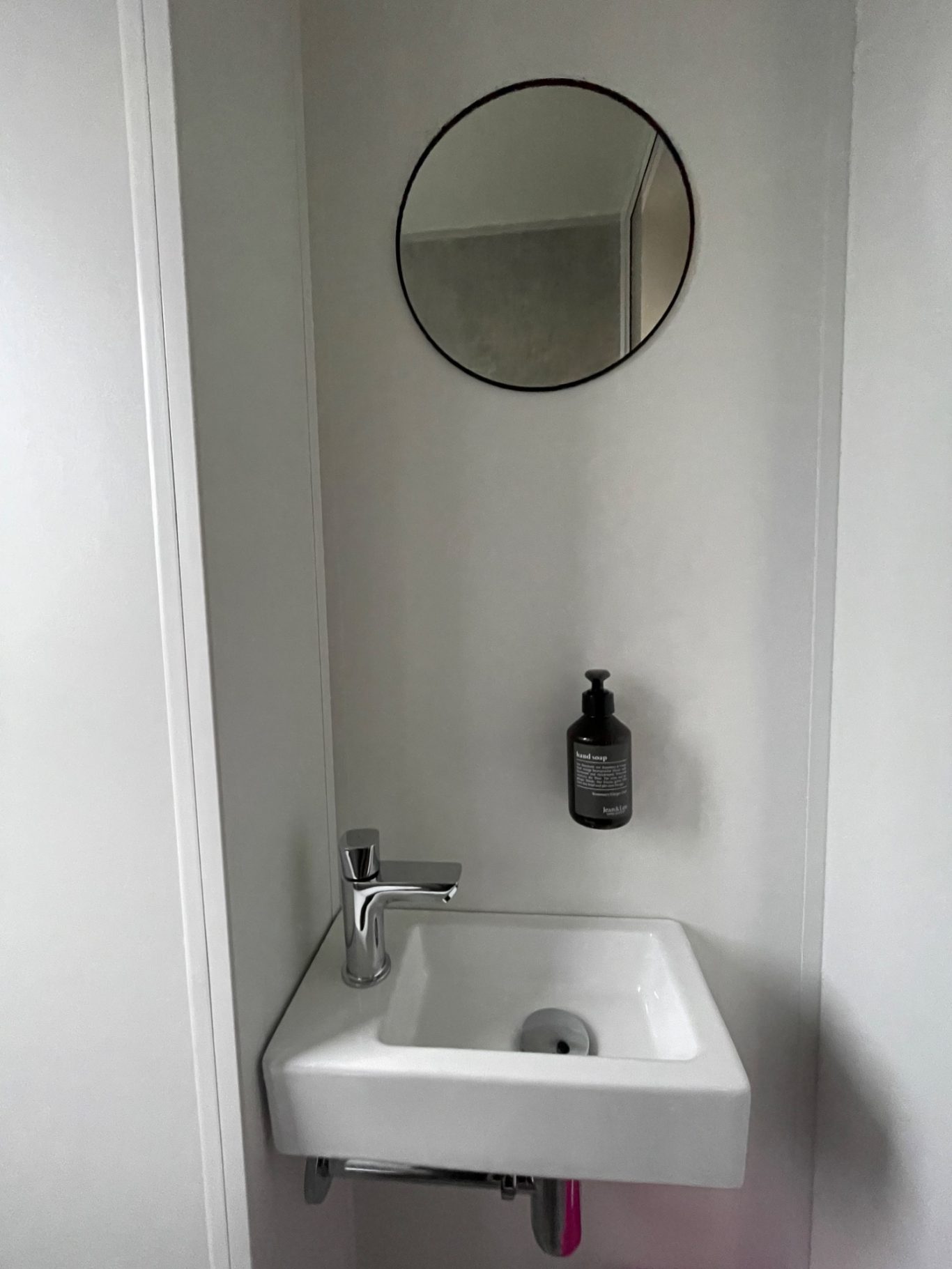 Toilette Kleine Toilette mit einem Waschbecken und einem runden Spiegel an der Wand.