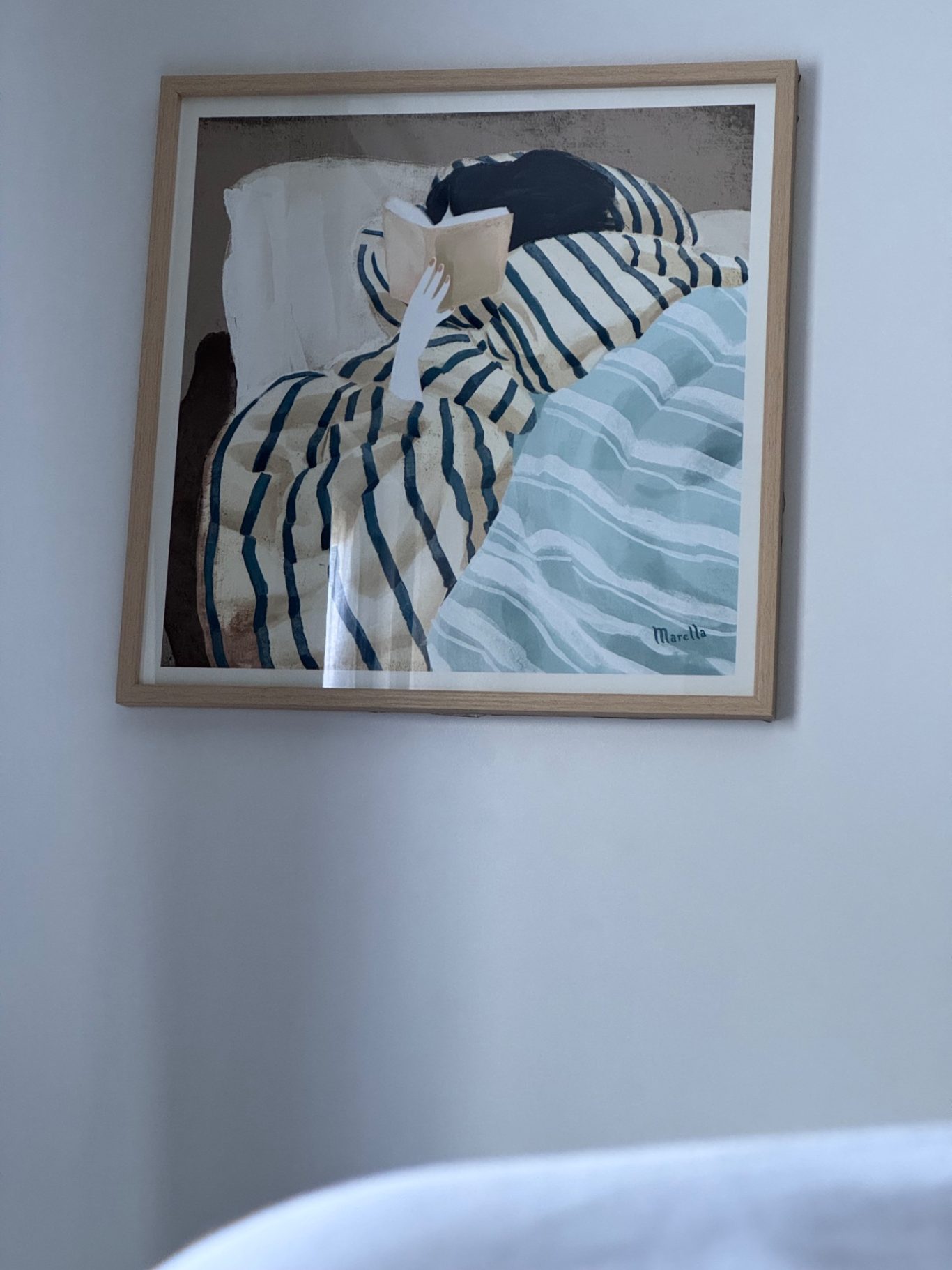 Einrichtungsdetailles Ein gerahmtes Bild einer gestreiften Decke und Kissen auf einem Bett.