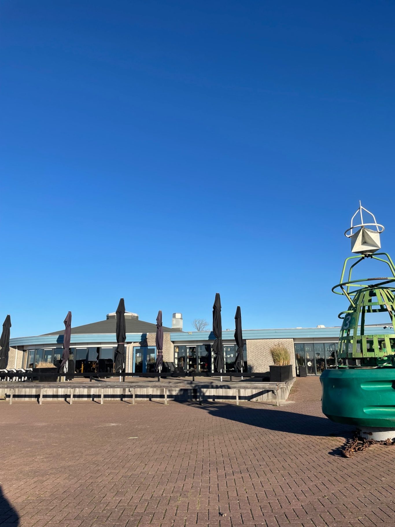 Haupthaus Helle Ansichtsfläche mit grüner Skulptur, modernen Gebäuden und klarem Himmel.