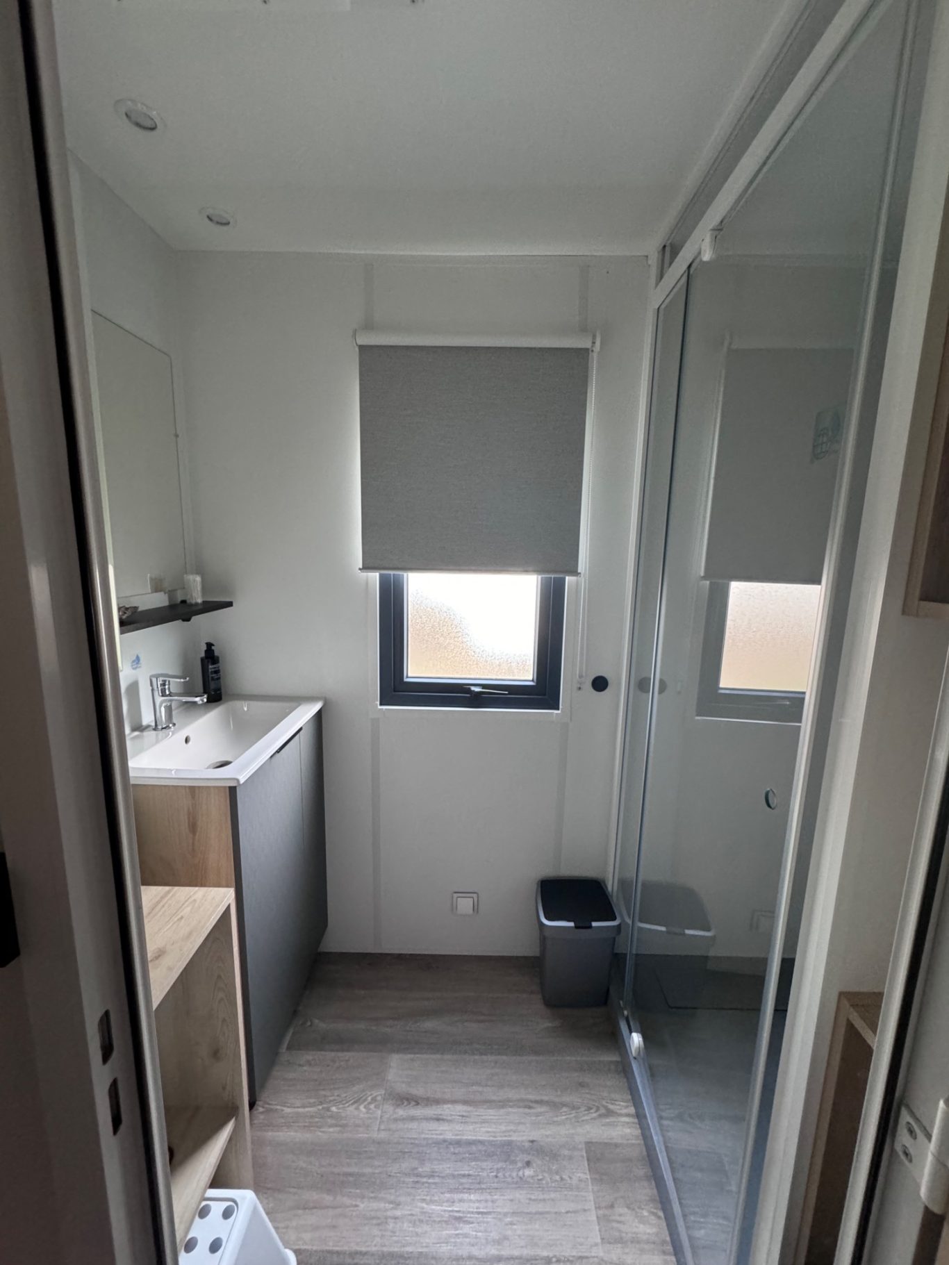 Badezimmer Kleines, modernes Badezimmer mit Dusche, Waschbecken und Fenster.