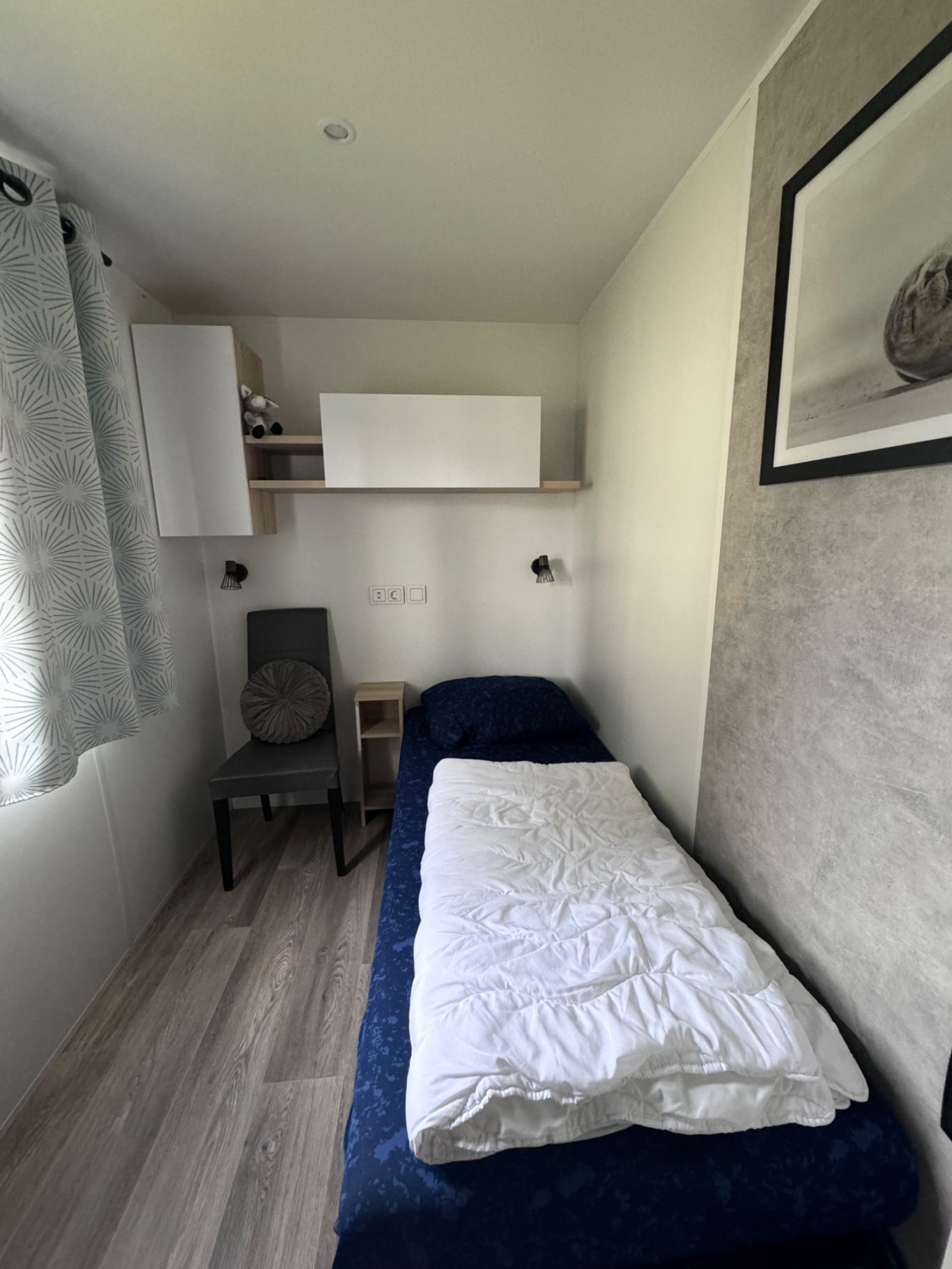 Schlafzimmer 2 Kleines Zimmer mit Einzelbett, Stuhl und Aufbewahrungsschrank, hell und modern eingerichtet.