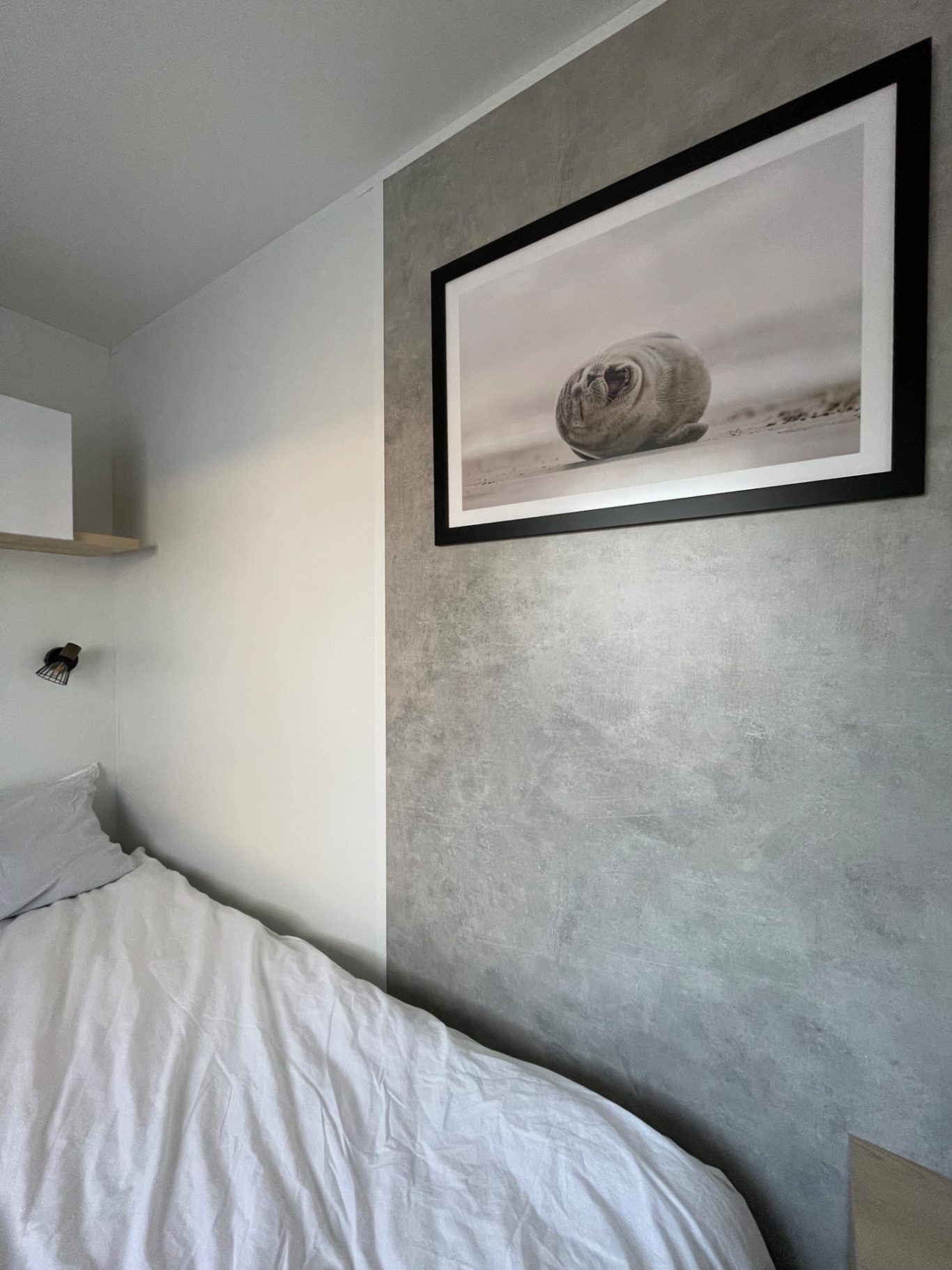Schlafzimmer 2 Ein schlichtes Schlafzimmer mit einem Bett und einem gerahmten Bild einer Felsformation.