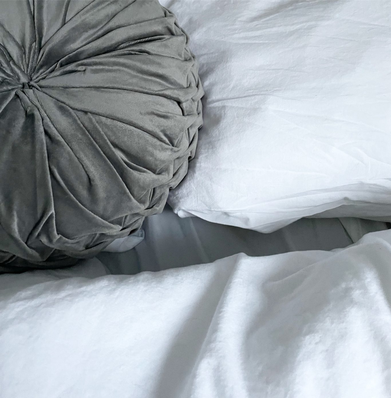 Schlafzimmer 1 Grauer Kissenbezug und zwei weiße Kissen auf einer Bettdecke.