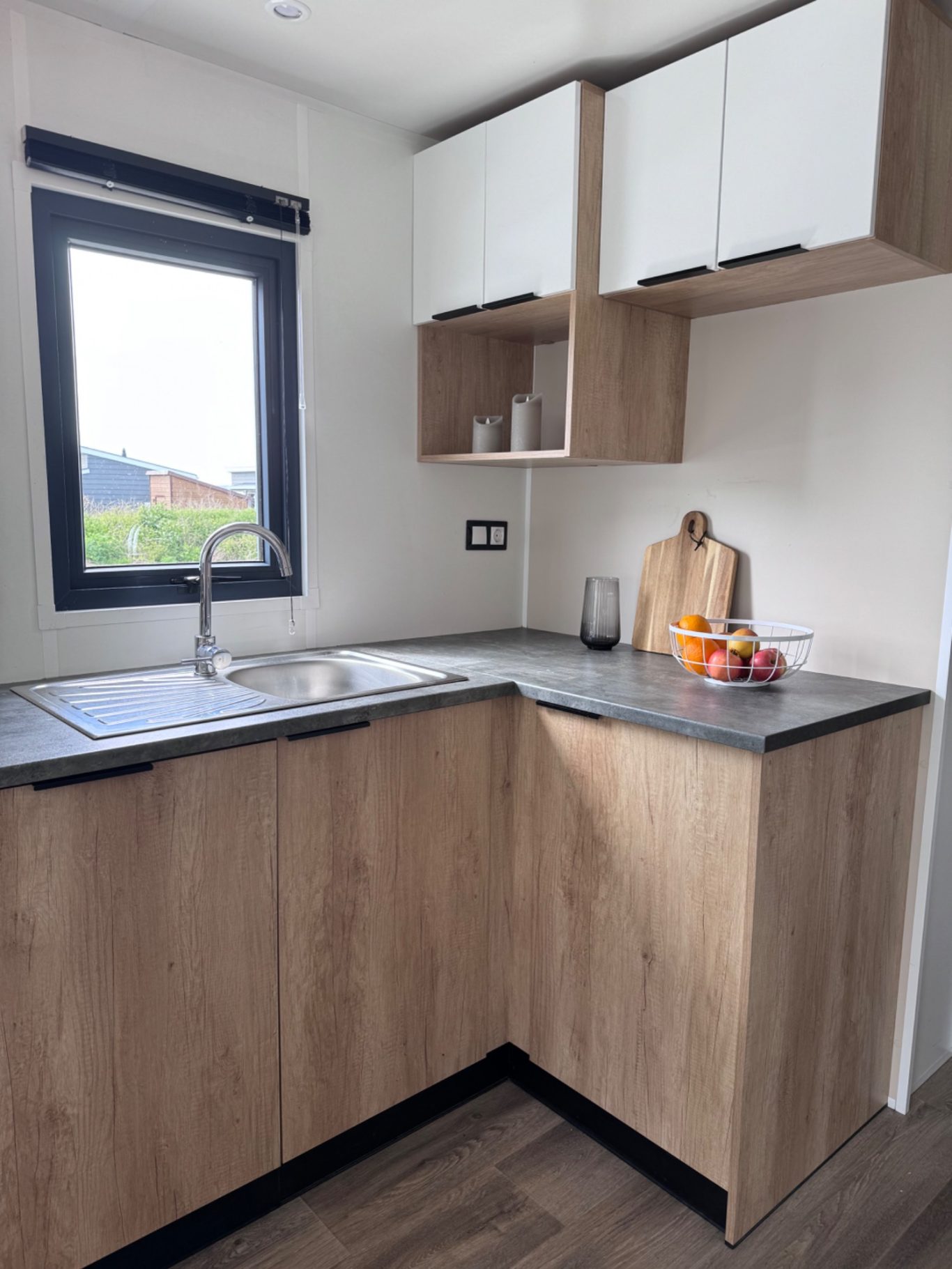 Küche Moderne Küche mit Holzschränken, Arbeitsfläche und Obstkorb auf dem Tisch.