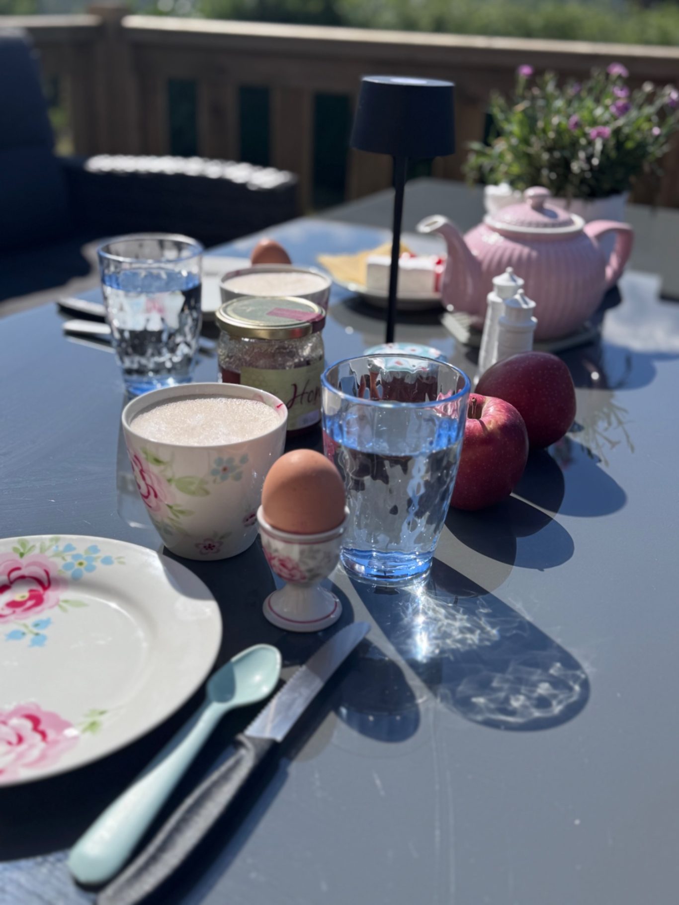 Impressionen Tischgedeck mit Tellern, Gläsern, Äpfeln, Eiern und einer Teekanne im Freien.